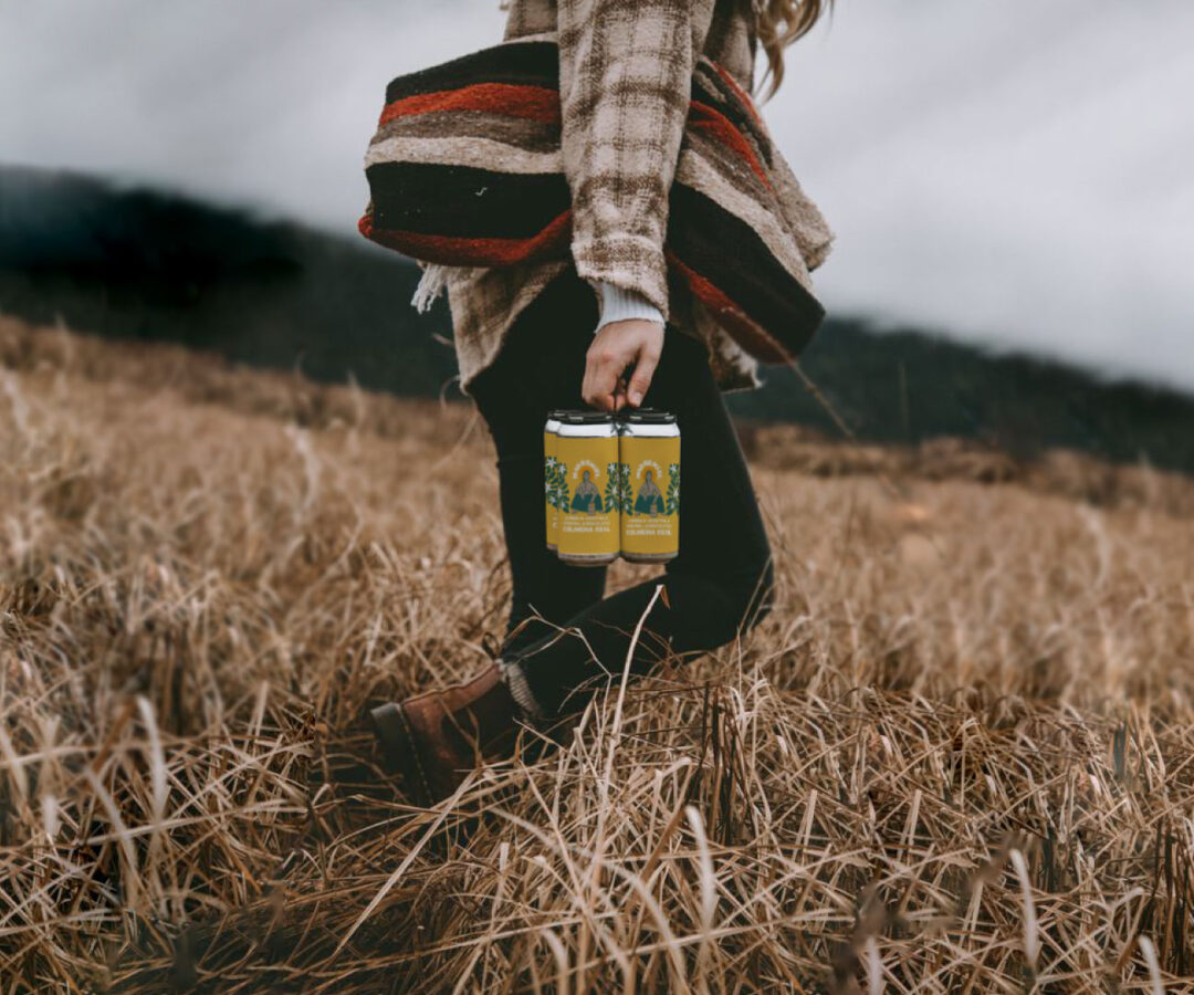 Diseño de packaging para Madremiel, hidromiel chilena agroecológica. Fotografía de producto en contexto natural con mujer caminando en paisaje rural. Branding por María Bunster.
